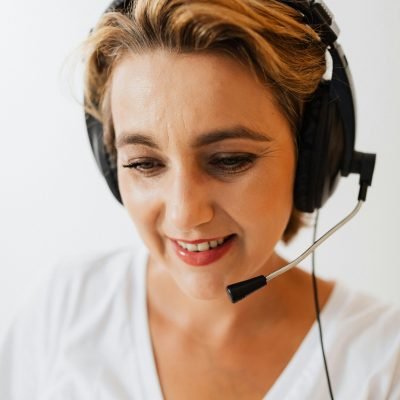 A woman wearing a headset smiles while working in customer service.